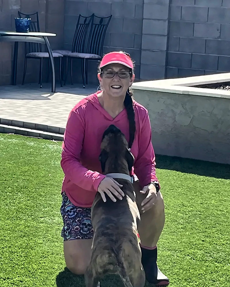 Britni kneeling on the turf with a brindle dog