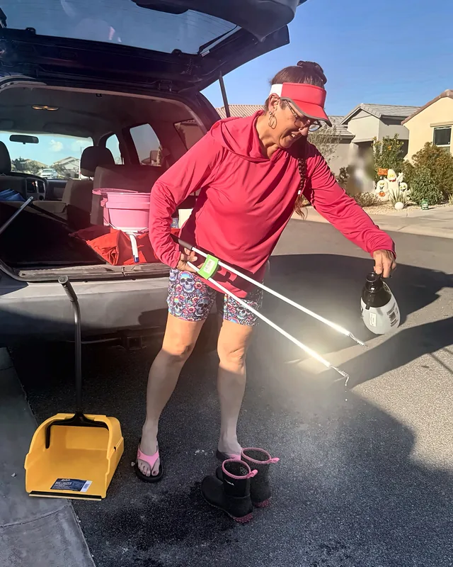 Britni spraying her scooper with sanitizer at her car